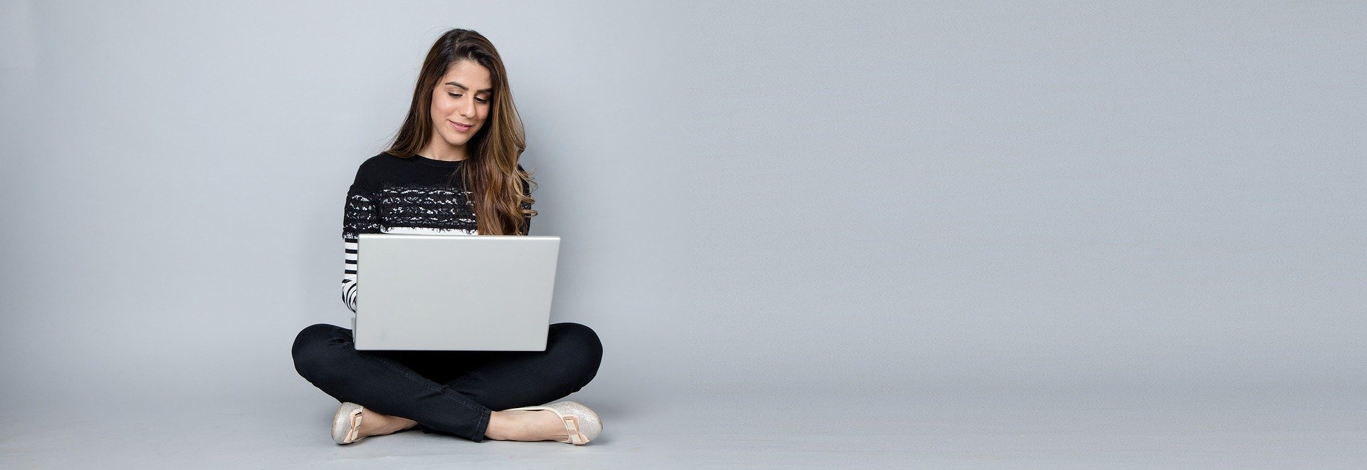 woman on laptop sitting against wall